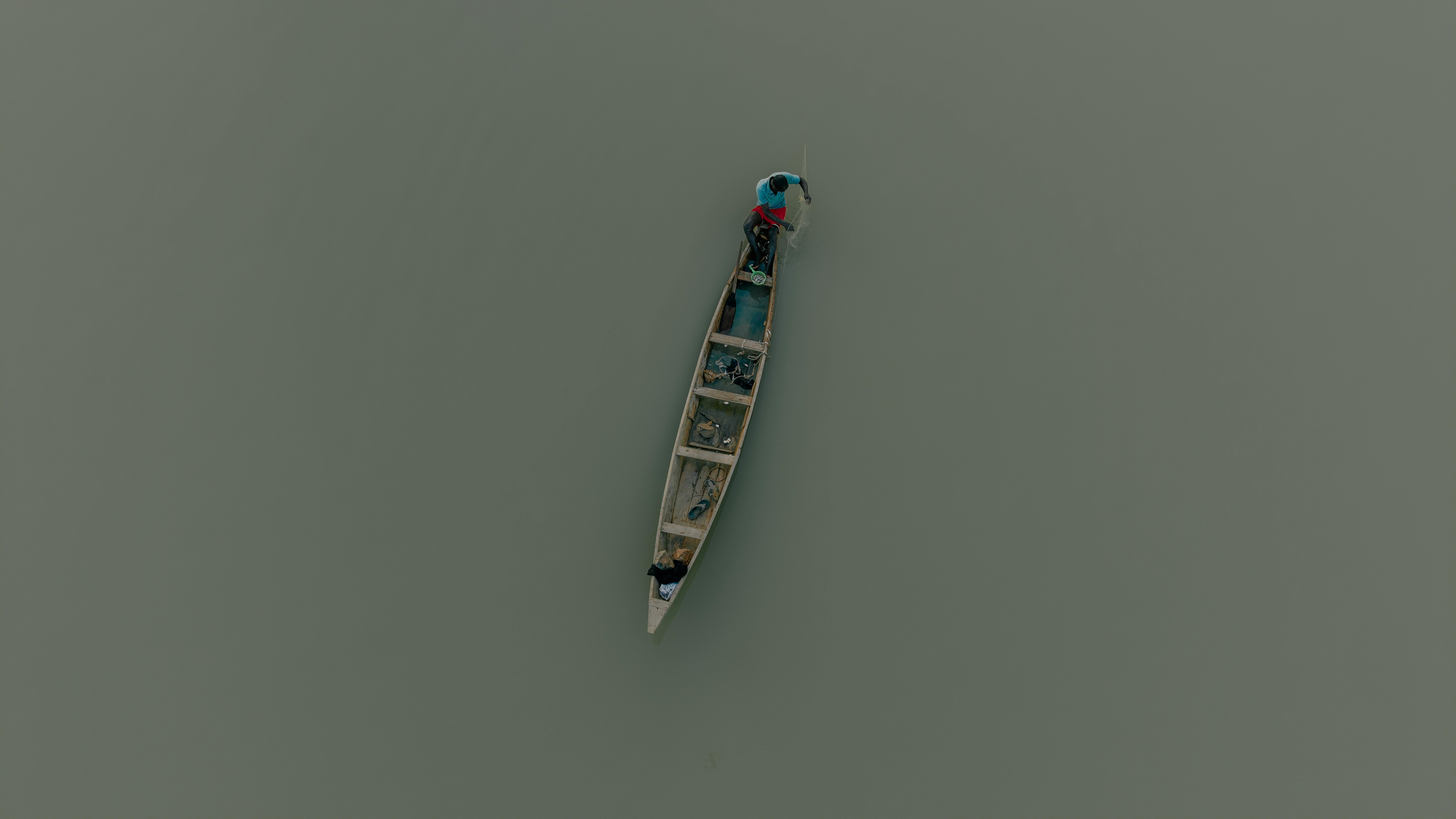 Free Top view of a canoe with fishermen paddling across a calm river surface. Stock Photo