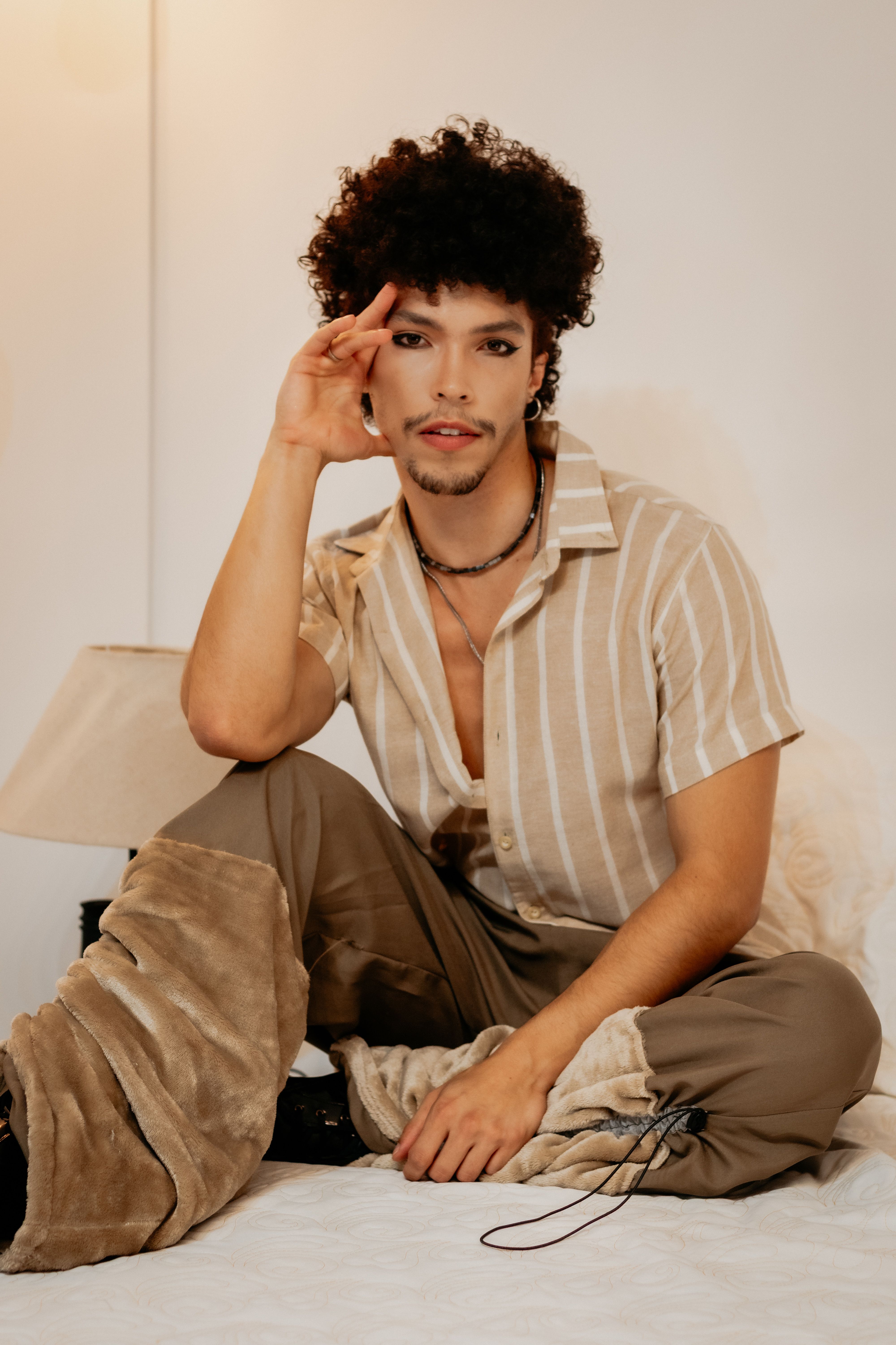 Elegant portrait of a young man sitting indoors, exuding confidence and style.