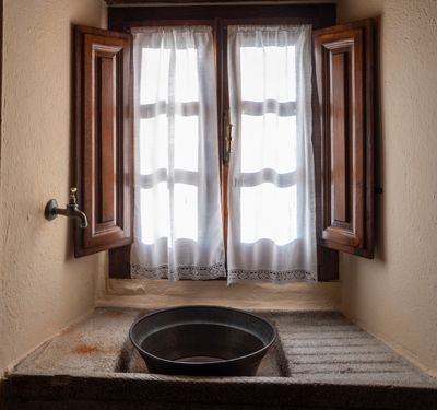 Stone sink beneath a wooden window in a rustic kitchen — tommy picone on Pexels