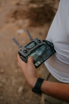 Close-up view of a man holding a remote control in an outdoor setting, operating a drone.