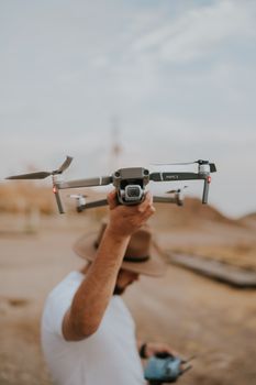 Man with a hat holding a DJI drone outdoors in a casual setting, ready for flight.