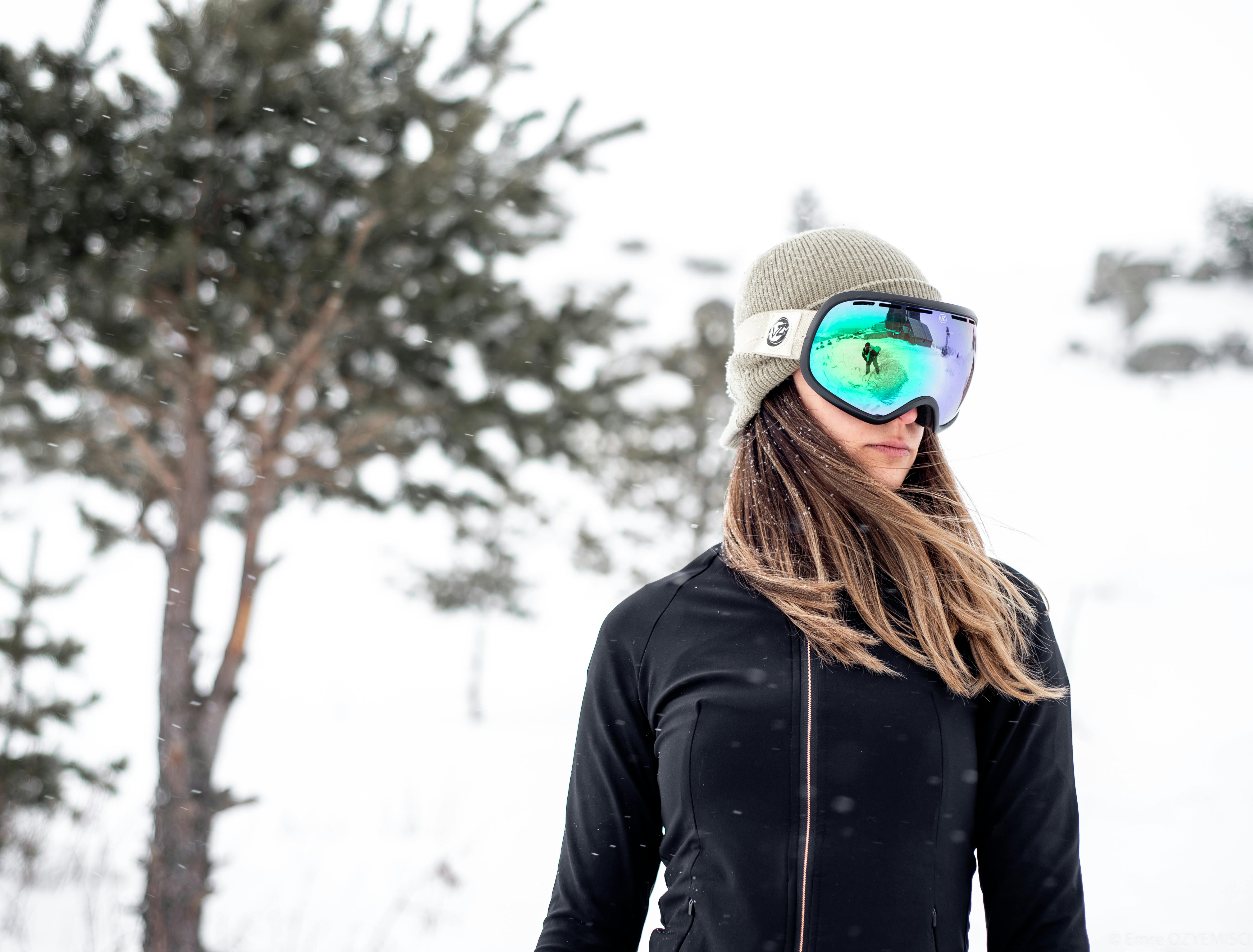 Outdoor portrait of a female skier in fashion gear during a snowy winter day.