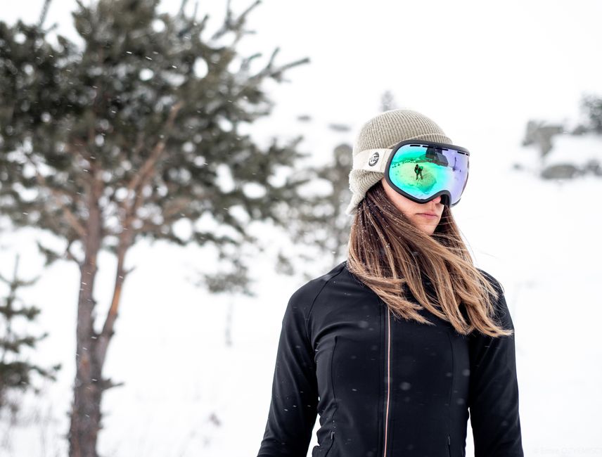 Outdoor portrait of a female skier in fashion gear during a snowy winter day.