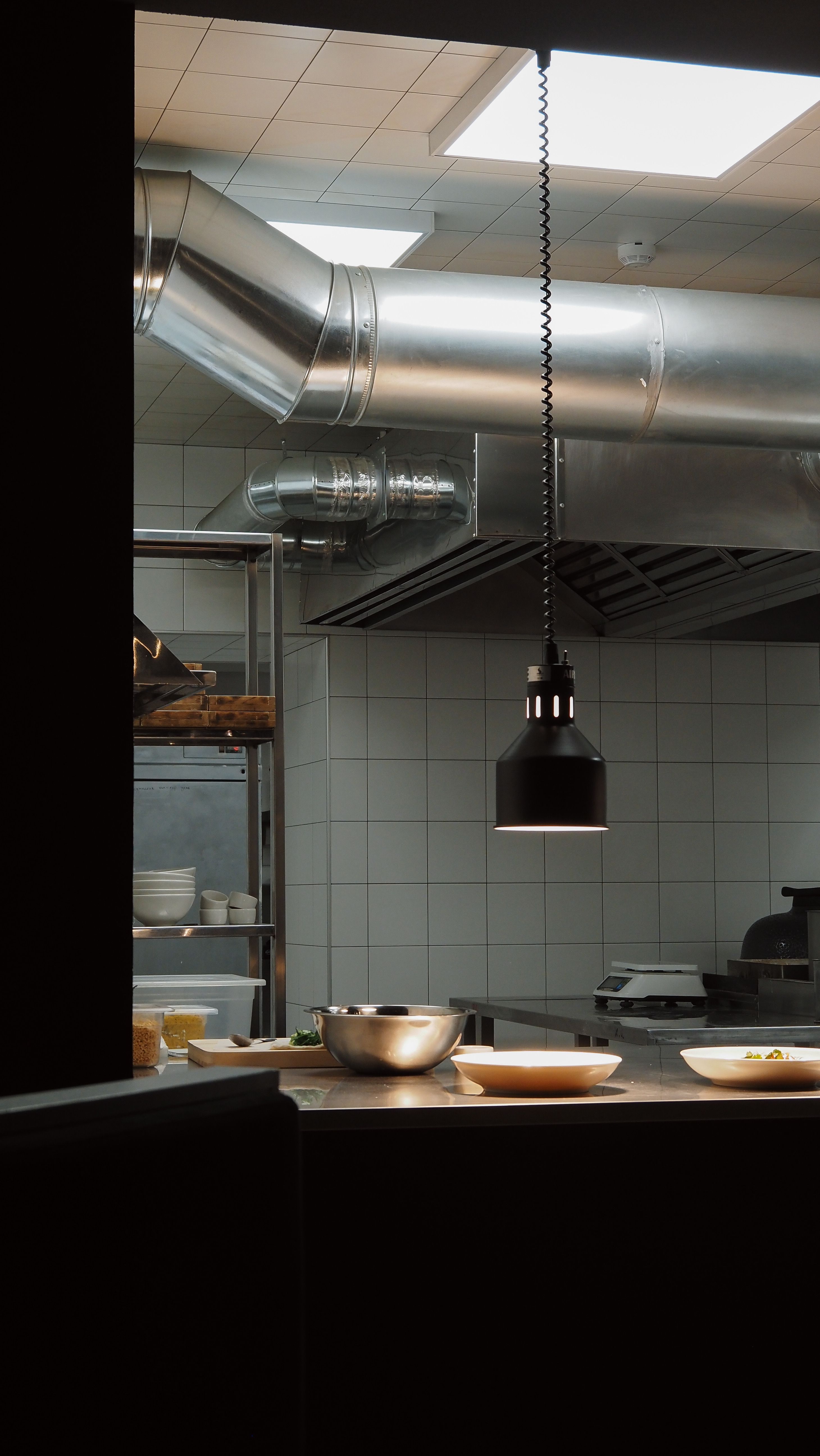 Poste de cuisson d'une cuisine professionnelle éclairé par la rampe lumineuse intégrée à la hotte d'extraction