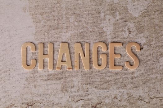 Wooden letters arranged to form 'Changes' on a textured, rustic surface.