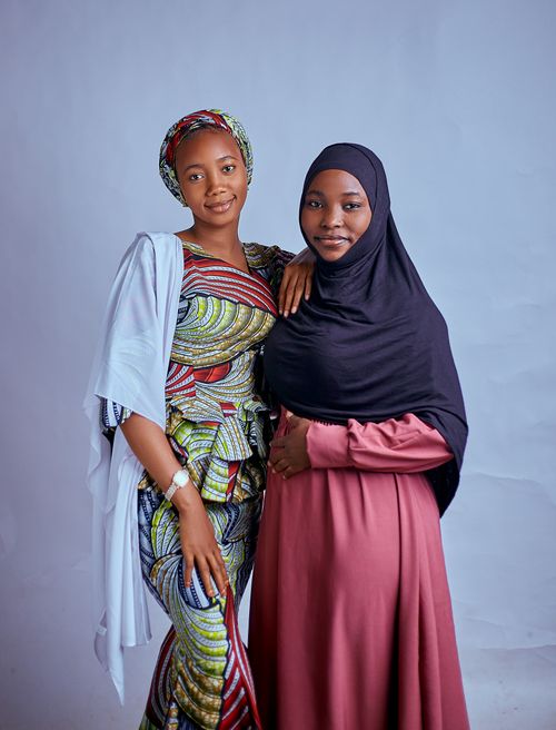 Free Two women in colorful traditional attire pose against a plain background. Stock Photo