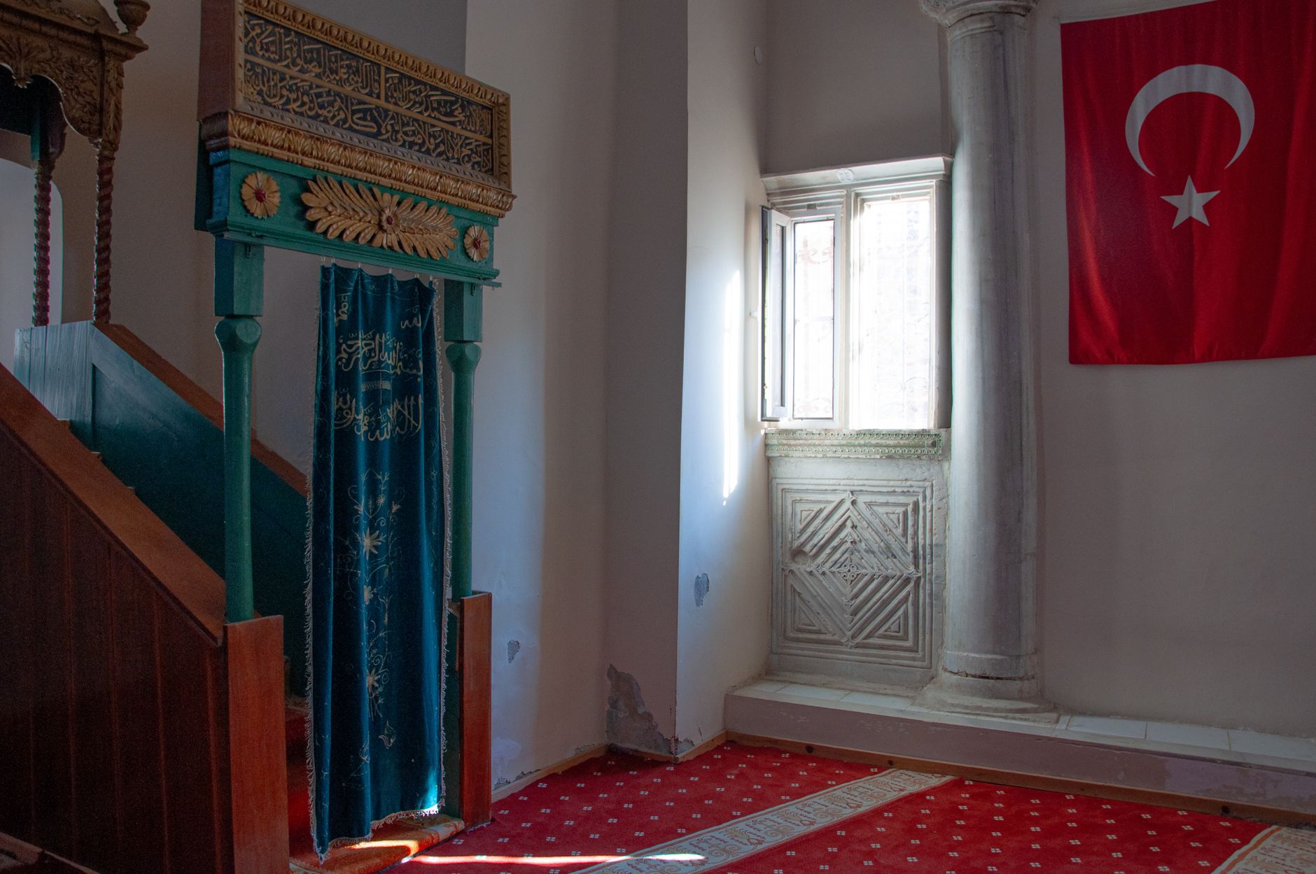 The historic interior of a mosque in Zeytinbağı, featuring traditional architecture and a Turkish flag.