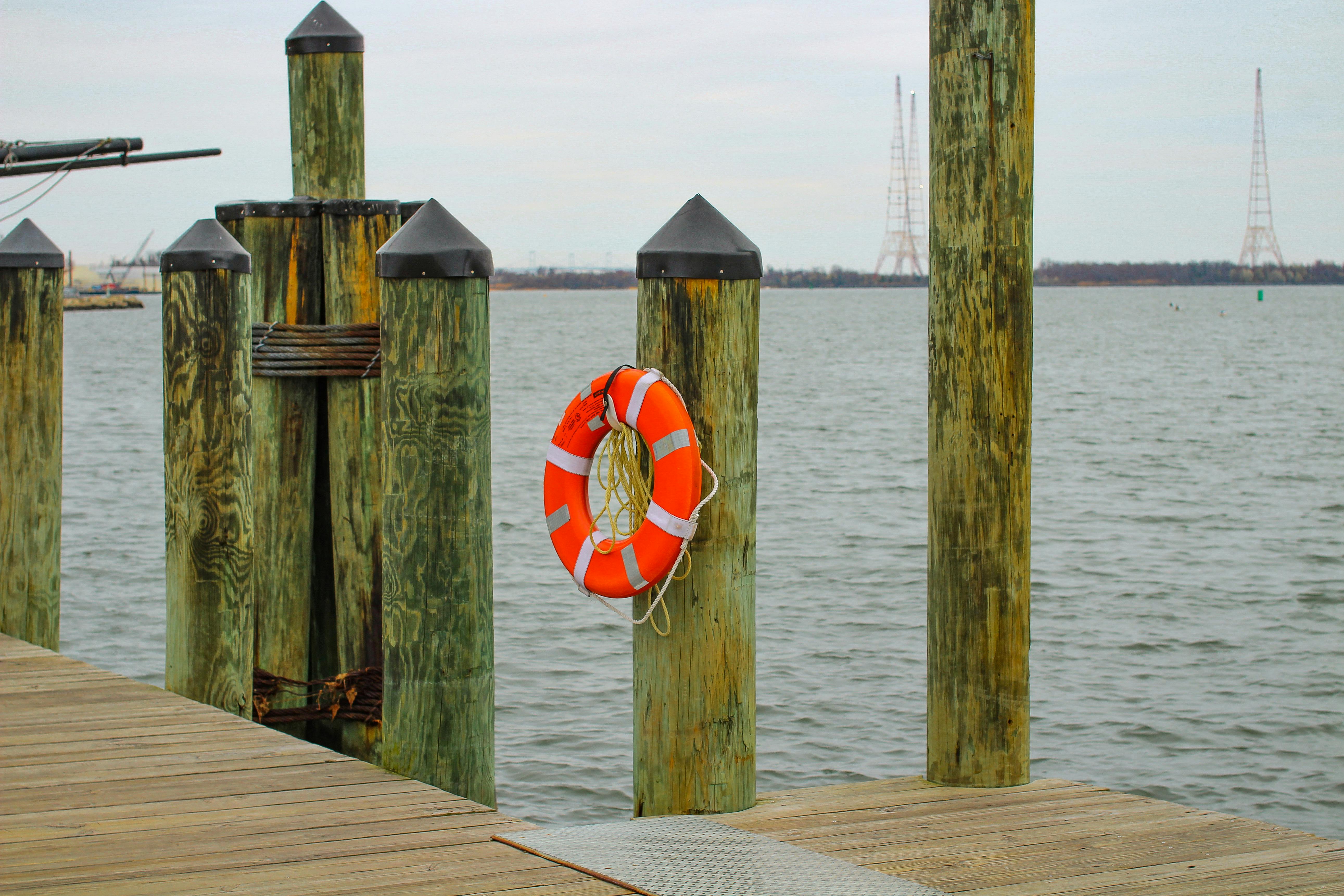 Wooden dock in Annapolis, Maryland with a bright orange life buoy overlooking the calm Chesapeake Bay.
