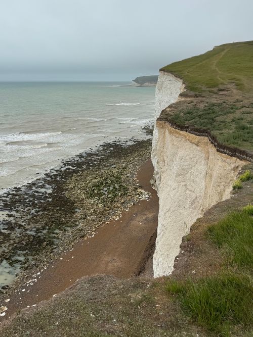 Free Scenic view of the iconic White Cliffs of Dover and coastline under a cloudy sky. Stock Photo