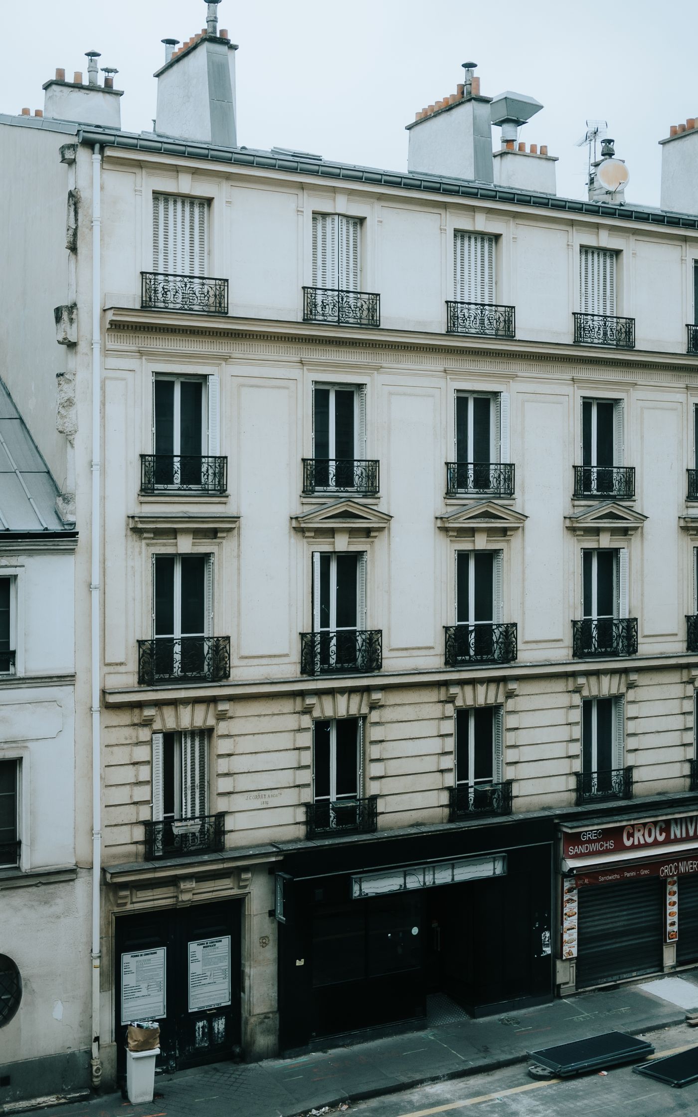 Façade d'immeuble parisien couleur crème avec balcons en fer forgé