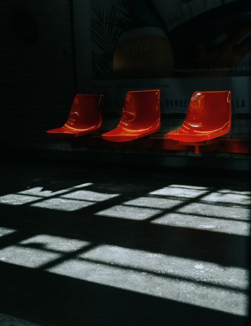 Free Red plastic chairs in a Paris metro station under dramatic shadow lighting. Stock Photo