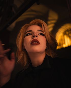 Stylish portrait of a woman with bold makeup under warm indoor lighting.