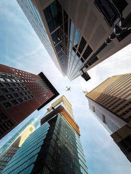 A dramatic worm's eye view of Frankfurt's modern skyscrapers with an airplane flying overhead.