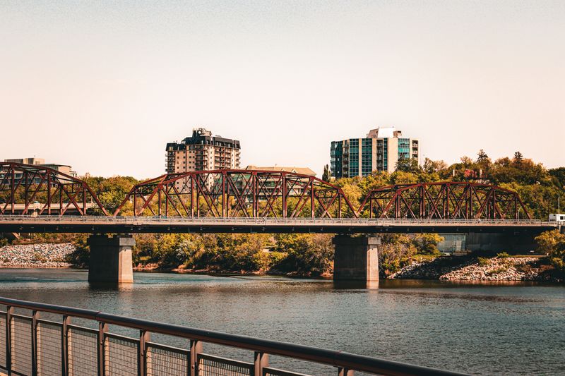 Steel bridge spanning a river through an urban landscape