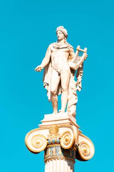 A stunning view of the Apollo statue atop a column against a clear blue sky in Athens, Greece.