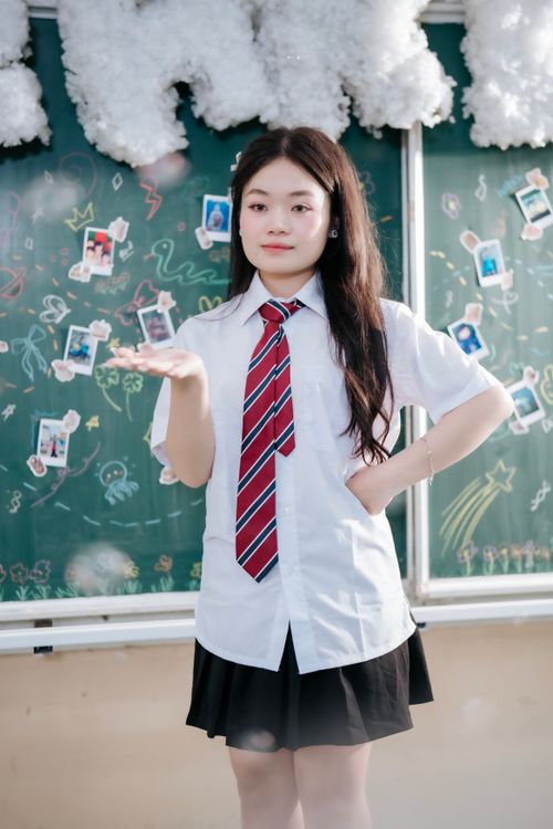 Free Portrait of a young Asian student in uniform against a creative chalkboard background. Stock Photo