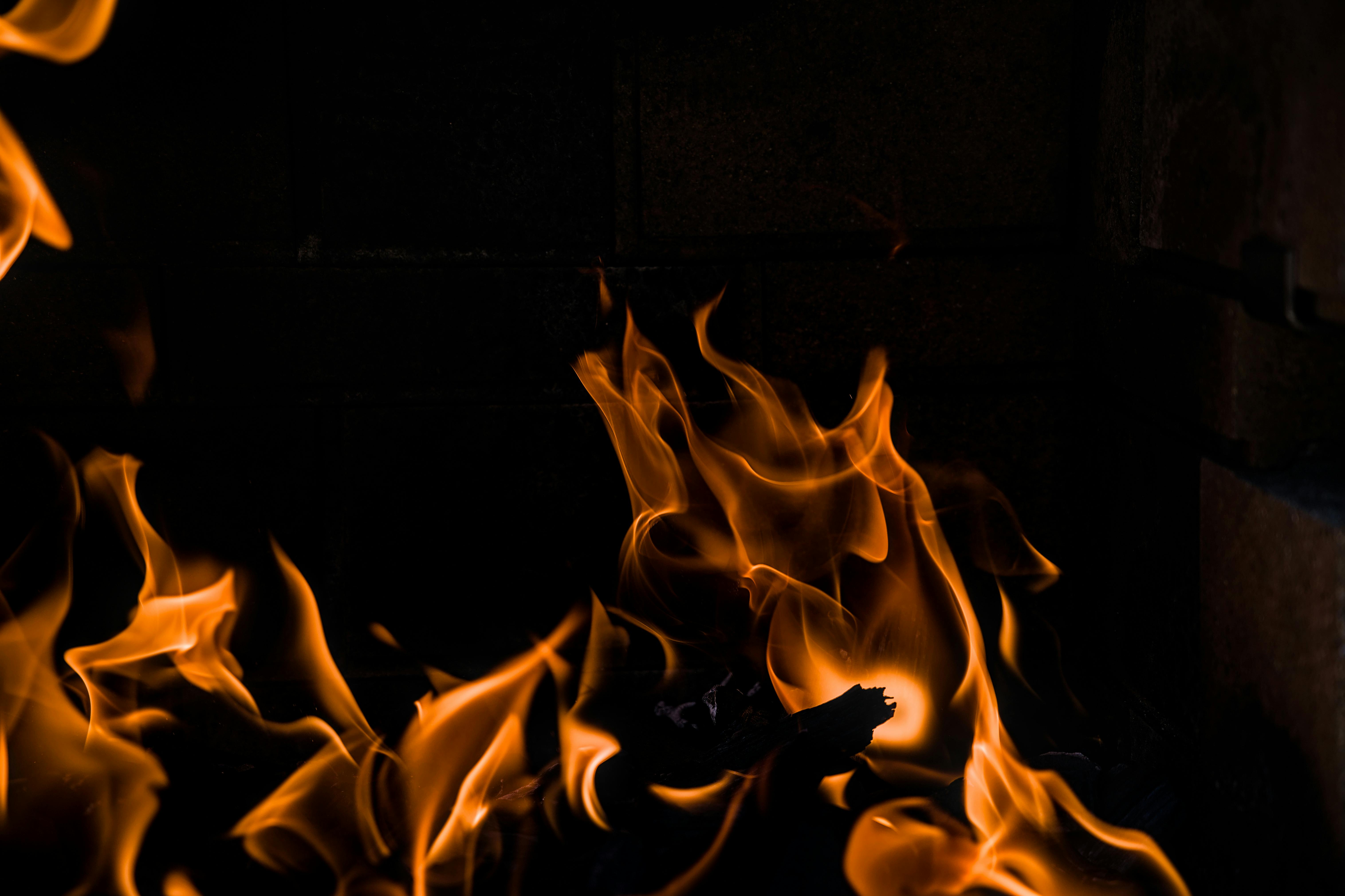 Capturer la danse vive des flammes orange dans un décor de cheminée sombre.