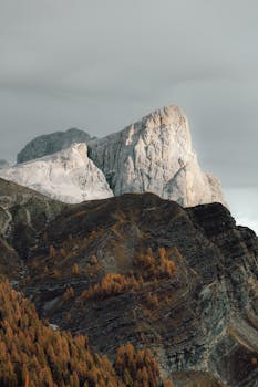 Stunning mountain peak surrounded by golden autumn foliage under a cloudy sky.