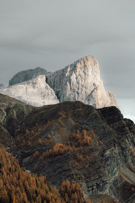 Stunning mountain peak surrounded by golden autumn foliage under a cloudy sky.
