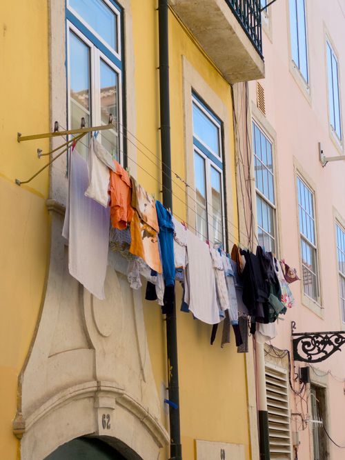 Free Vivid laundry drying on wires against a bright urban building facade. Stock Photo