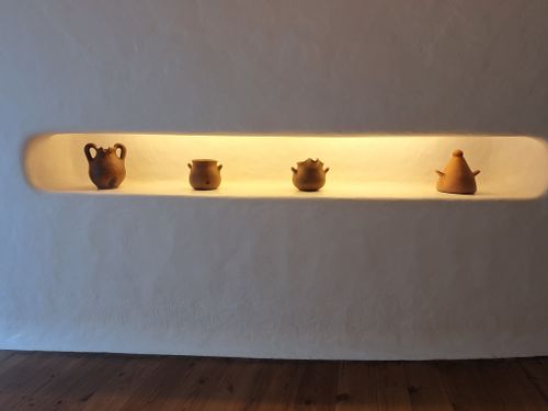 Free Four clay pots displayed on a recessed, illuminated shelf within a minimalist interior. Stock Photo
