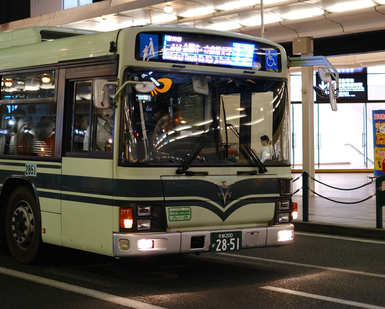 A city bus at night with illuminated signs in an urban environment.