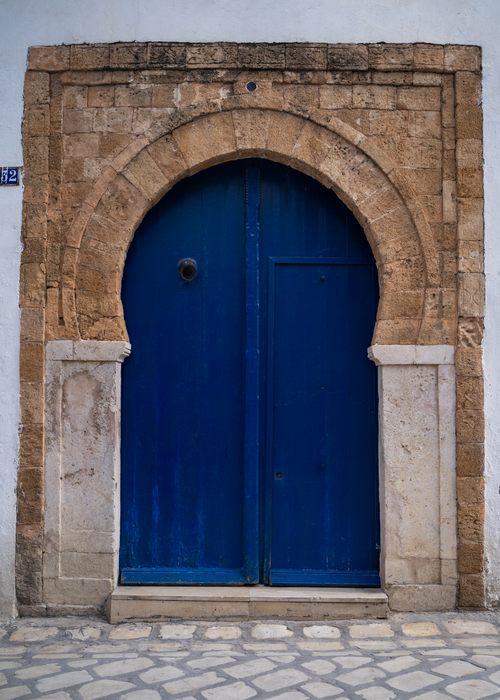 Free A vibrant blue door set within a rustic stone archway, typical of Medina architecture. Stock Photo