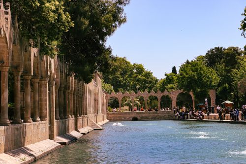 Free Tranquil scene of ancient stone columns beside a picturesque reflecting pool with trees. Stock Photo