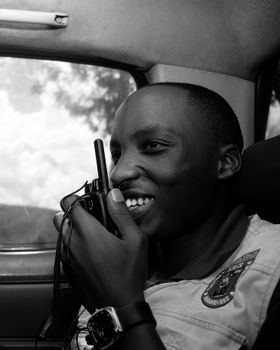 Black and white photo of a man using a radio in Rwanda, showcasing communication.