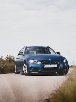 Front view of a stylish blue car on a rural road, showcasing sleek design and modern aesthetics.