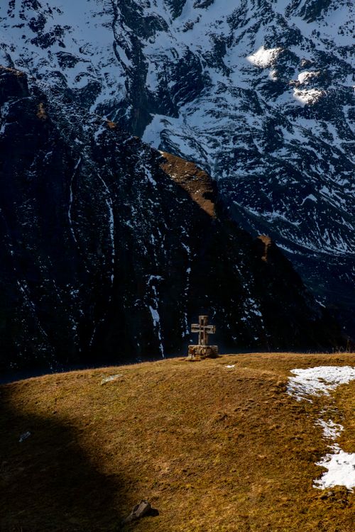 Free A captivating view of a wooden cross on a hill against the snow-capped Austrian Alps. Stock Photo