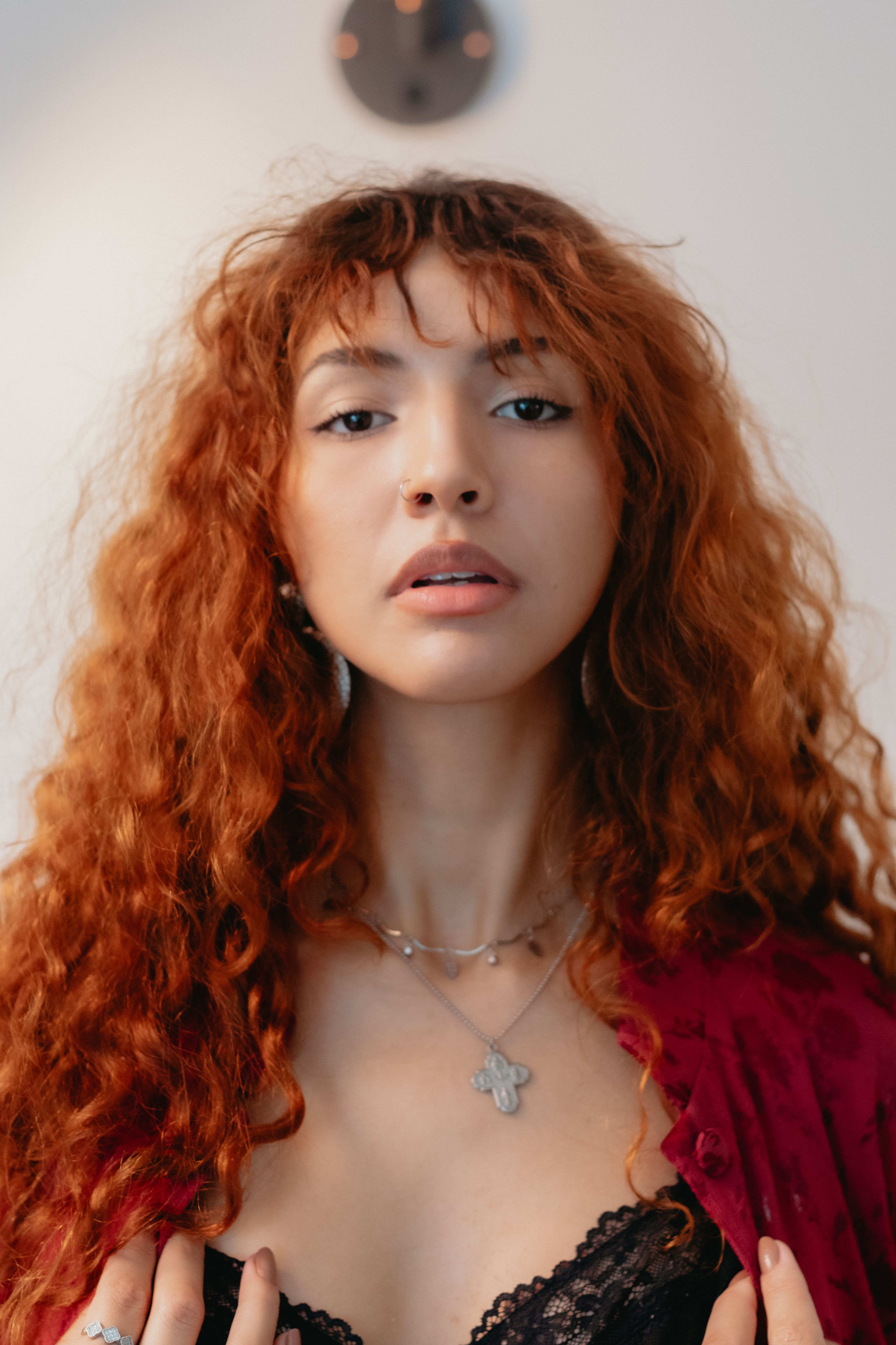 Captivating close-up portrait of a woman with red curly hair and stylish accessories indoors.