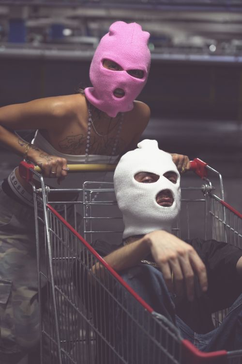 Free A striking photo of two masked individuals posing with a shopping cart in an urban setting. Stock Photo