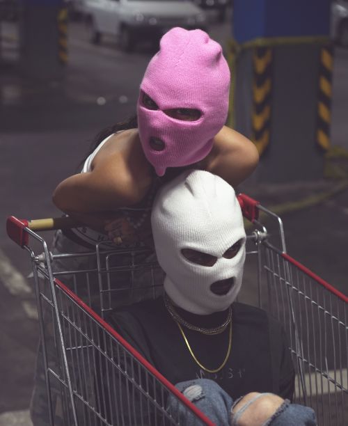 Free Photo of two people wearing ski masks inside a shopping cart in an urban setting. Stock Photo