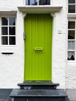 A striking lime green door on a historic building facade in Bruges, Belgium.