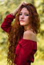 一位留着长卷发、穿着时尚红色上衣的女人，在户外摆姿势的肖像