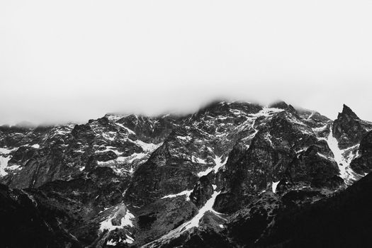 Stunning black and white photo of a rugged mountain range shrouded in clouds.
