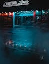 雾蒙蒙的夜晚，城市里霓虹灯映照着店面，灯光洒在潮湿的人行道上