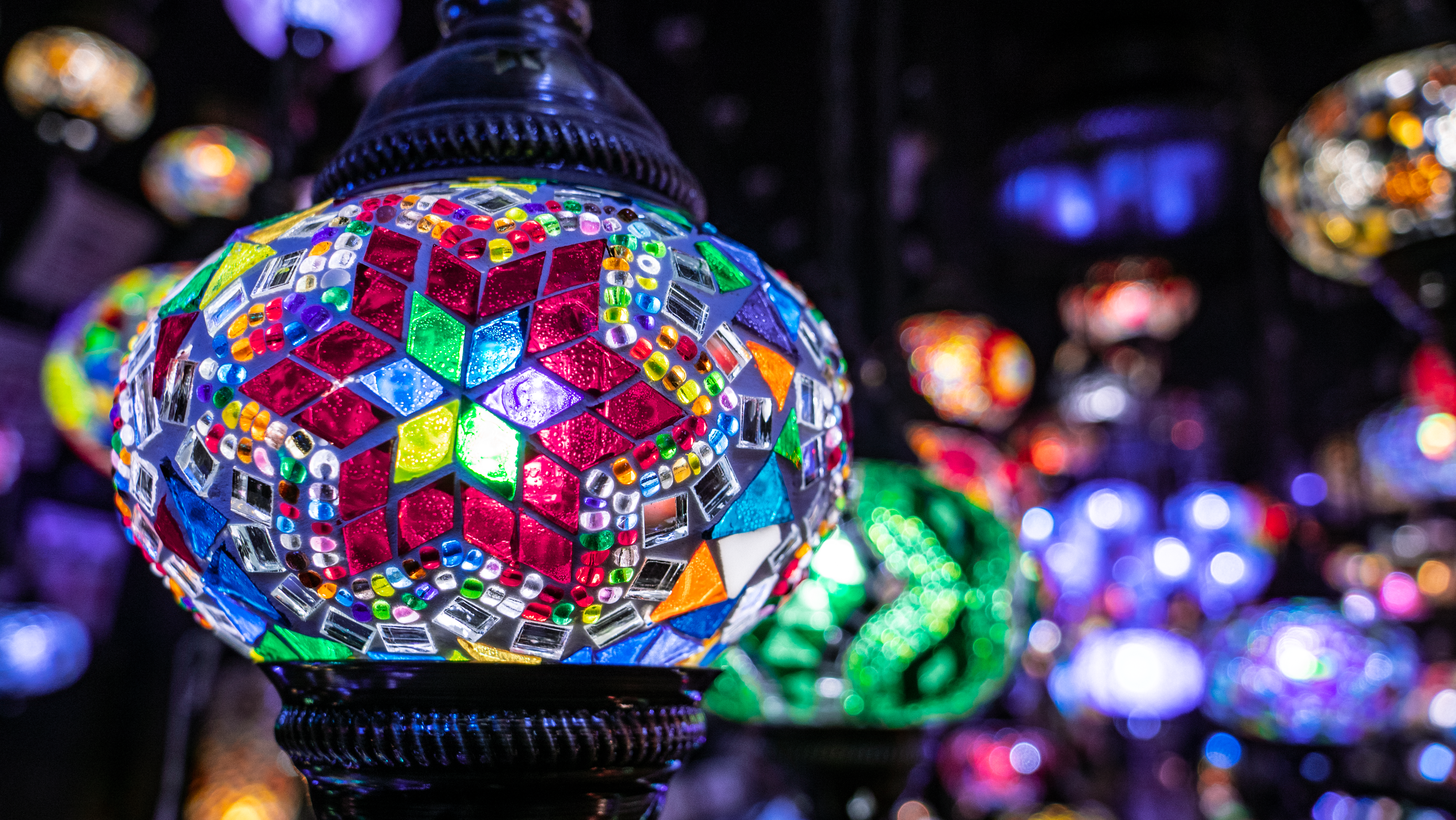 Colorful mosaic lamps illuminate a night market scene in London, England.