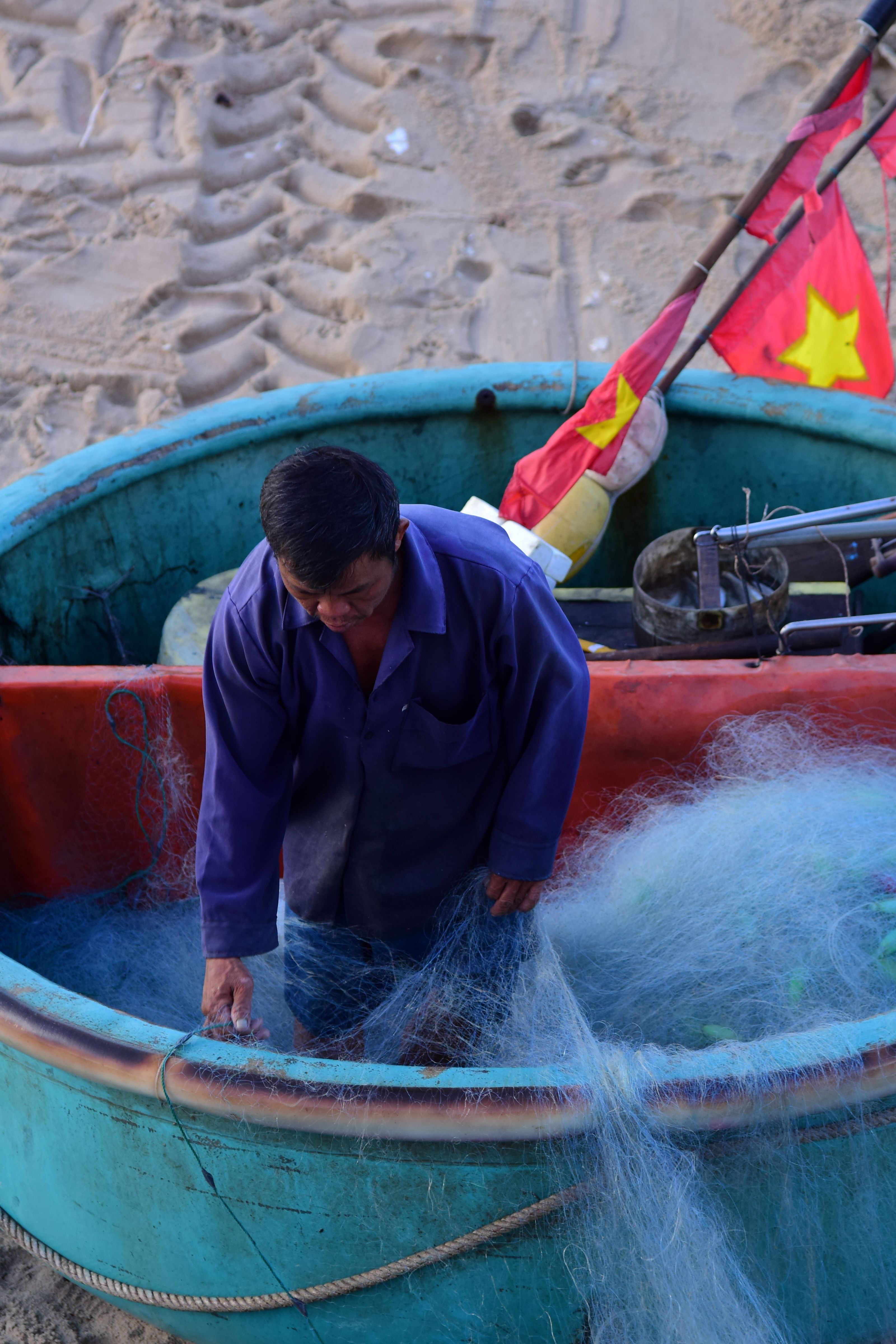 Fisherman sorting net in traditional Vietnamese boat · Free Stock Photo