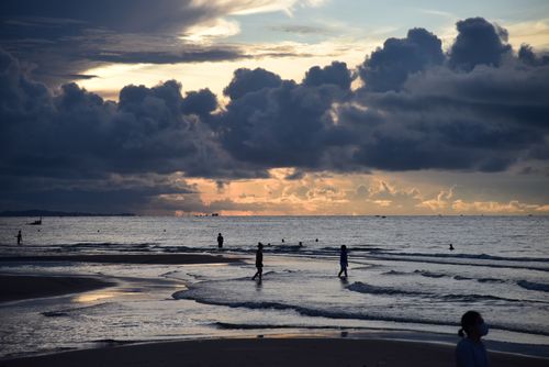 Free Silhouettes on the beach during a dramatic sunset with heavy clouds. Stock Photo