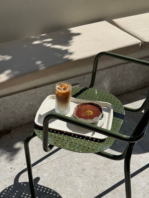 Elegant cafe scene with iced latte and tiramisu under soft sunlight.