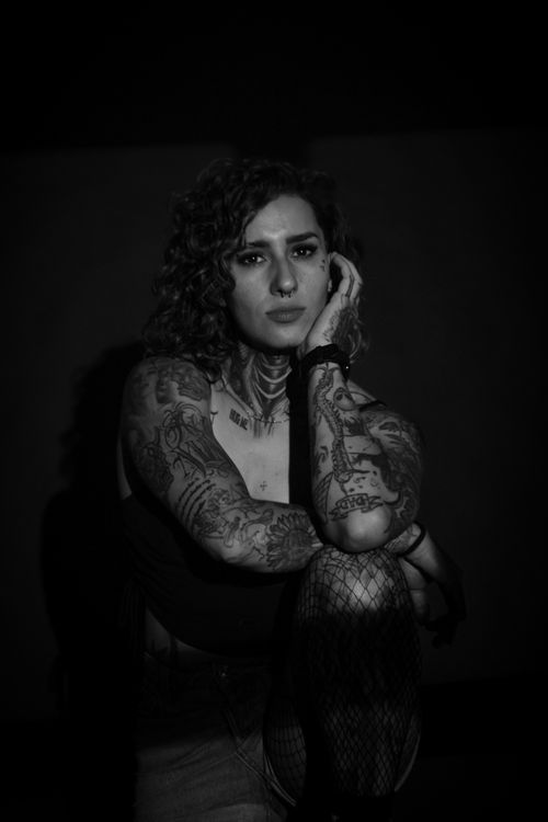 Free Portrait of a tattooed woman in a black and white setting, exuding confidence and style. Stock Photo