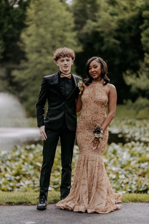 Free Stylish couple dressed in formal attire posing outdoors near pond. Perfect for prom themes. Stock Photo