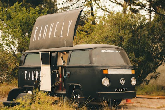 Vintage coffee van parked outdoors with foliage backdrop, perfect for lifestyle themes.