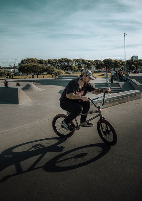 Free Energetic BMX cyclist maneuvering through a vibrant urban skate park on a sunny day. Stock Photo
