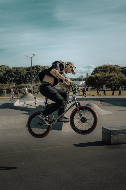 Free A BMX rider executing a jump at a vibrant outdoor skatepark under a clear sky. Stock Photo