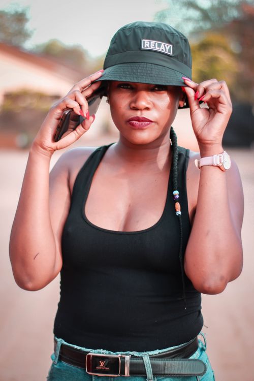 Free Portrait of a fashionable woman wearing a bucket hat and tank top outdoors. Stock Photo