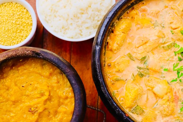 Colorful Brazilian Moqueca with sides on wooden table. Perfect for culinary and cultural themes.