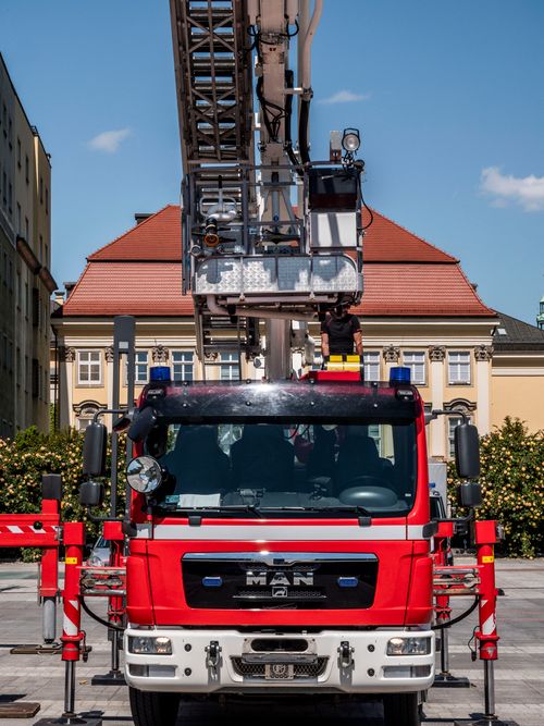 Free Front view of a red fire truck with an extended ladder outdoors in a city center. Stock Photo